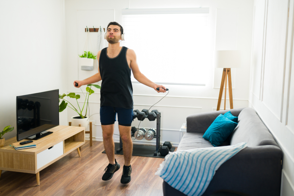 Los 7 Ejercicios Cardiovasculares Más Efectivos Para Quemar Grasa Un hombre haciendo ejercicio aeróbico saltando a la comba en casa